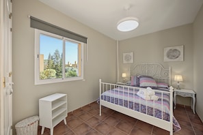 A bedroom with a bed, two bedside tables, a window, and a white shelf unit. - Casa Tartessos with Pool and Parking in Costa Ballena (Rota)