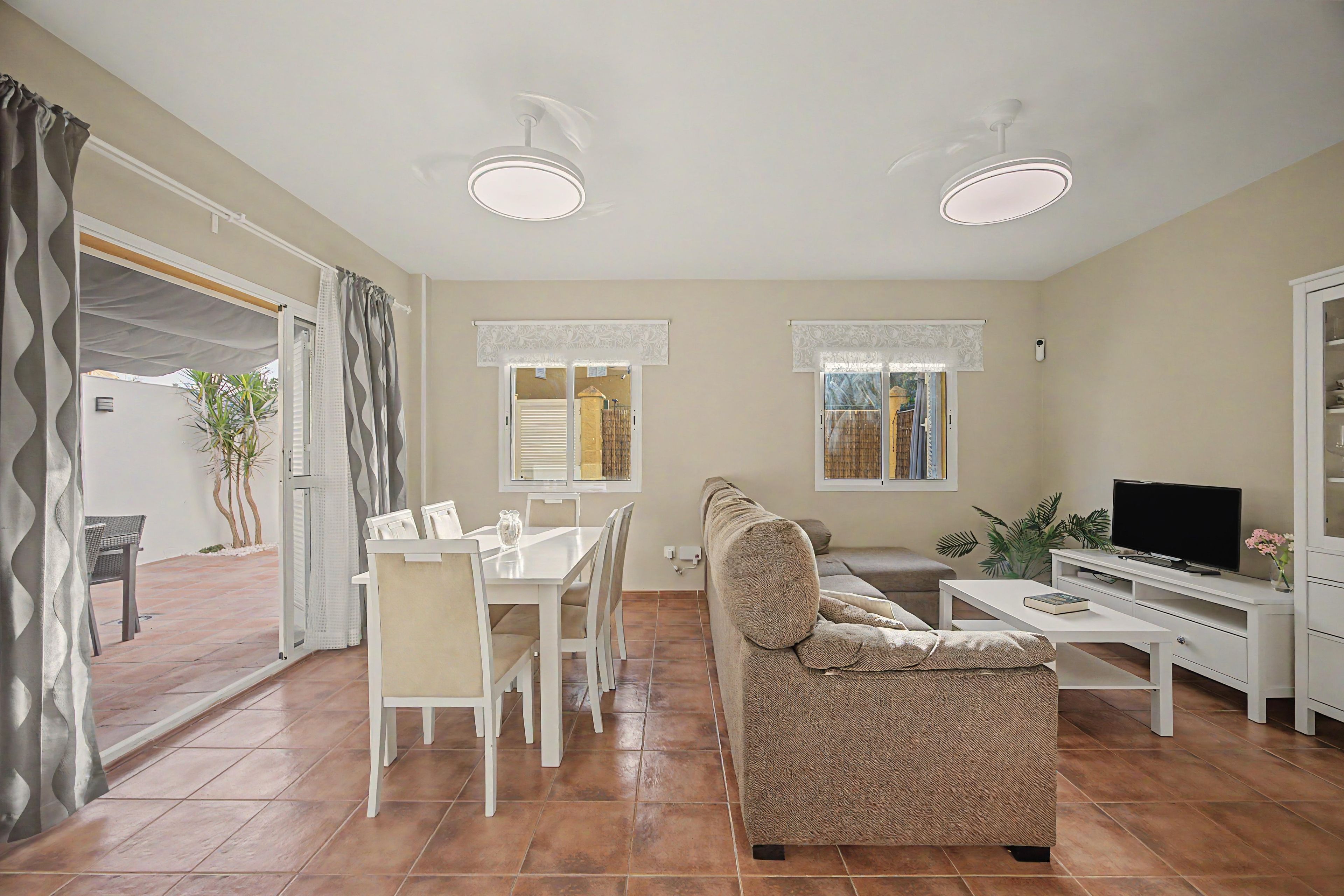 A living room with a sofa, TV, and dining area with chairs and a table.