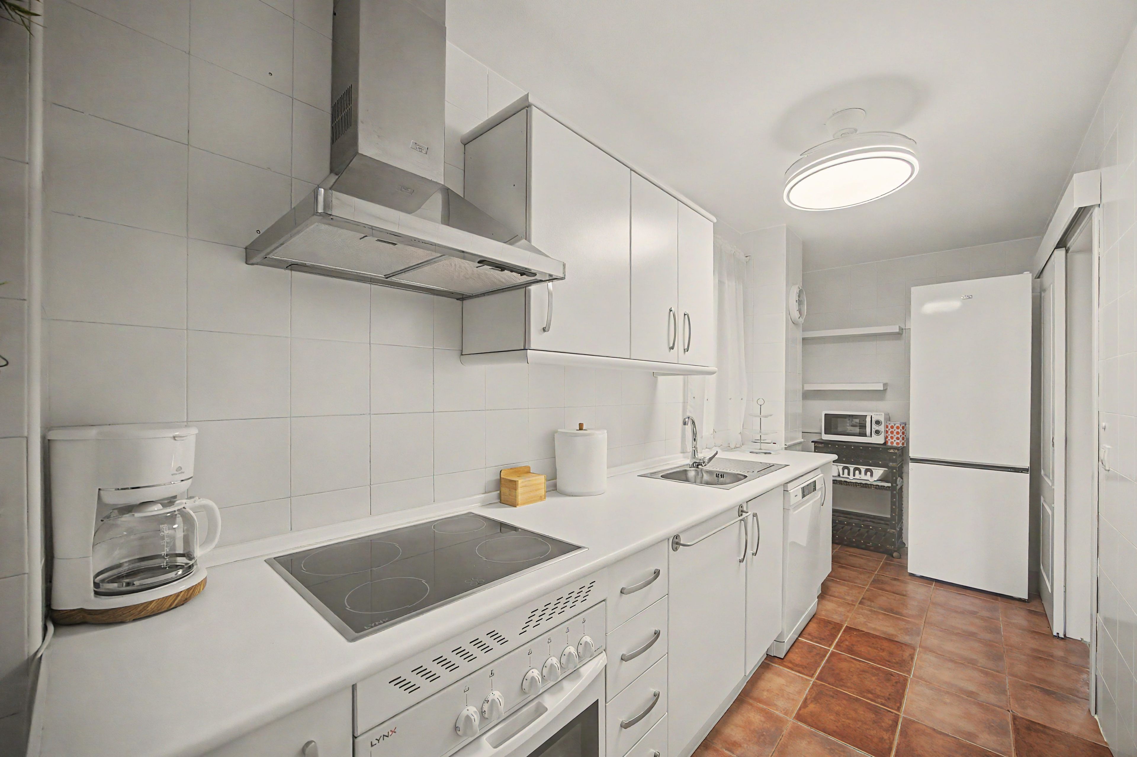 A modern kitchen with white cabinetry, a built-in stove, and a microwave.