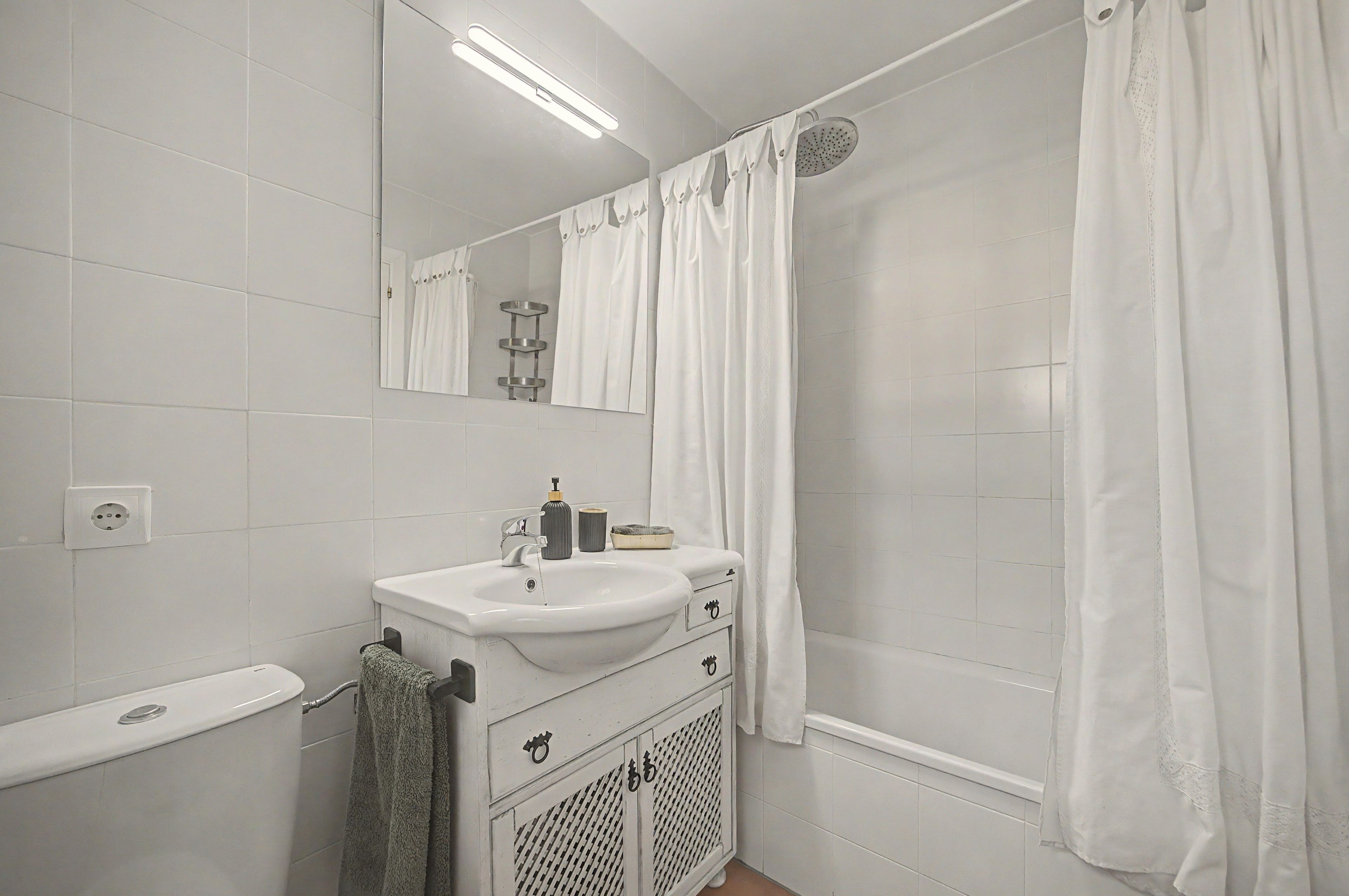 A bathroom with a white sink, mirror, and shower curtain.