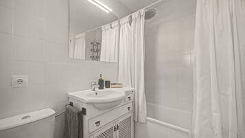 A bathroom with a white sink, mirror, and shower curtain.