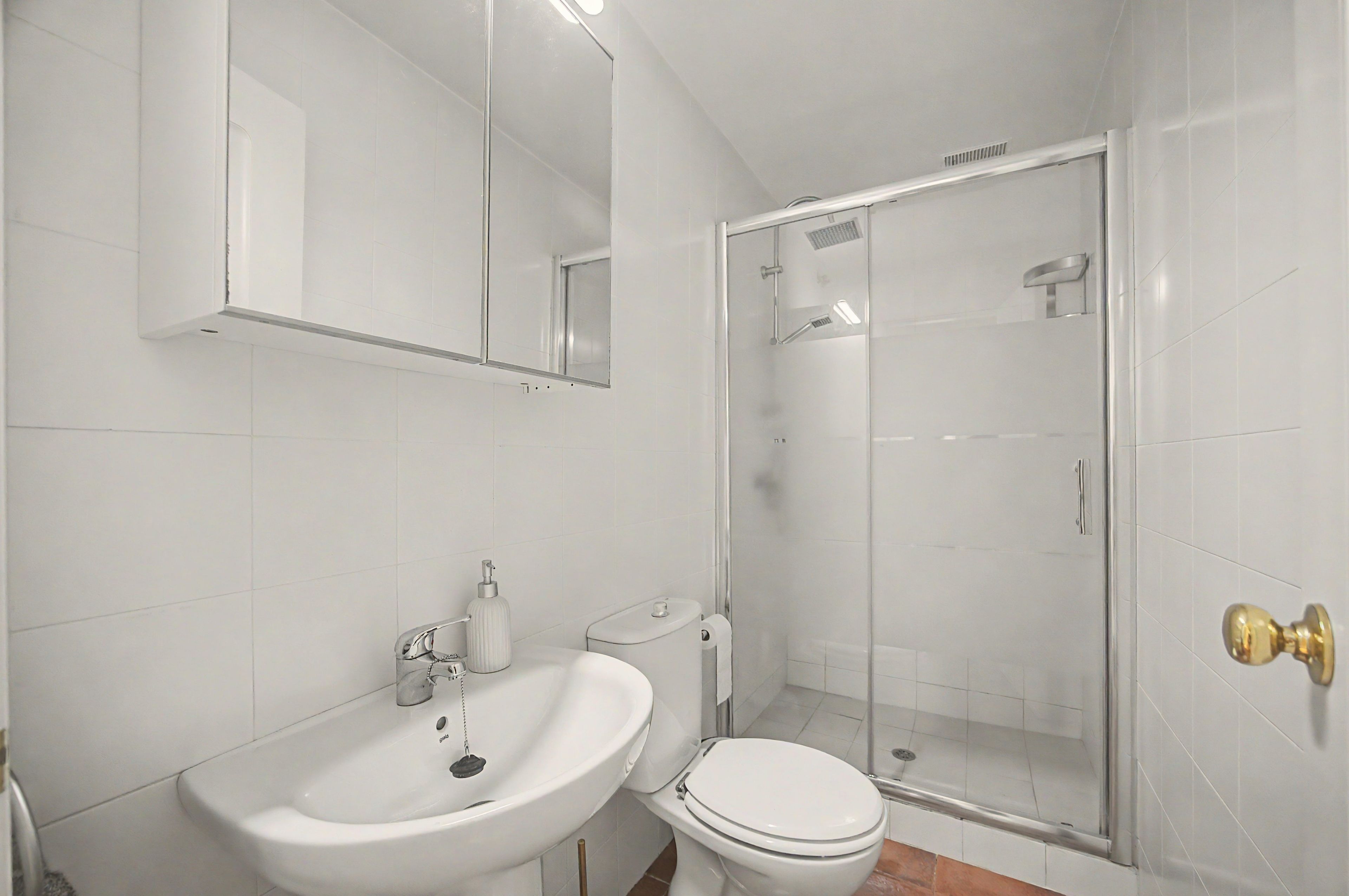 Une salle de bain équipée d’un lavabo, de toilettes et d’une douche à parois de verre.