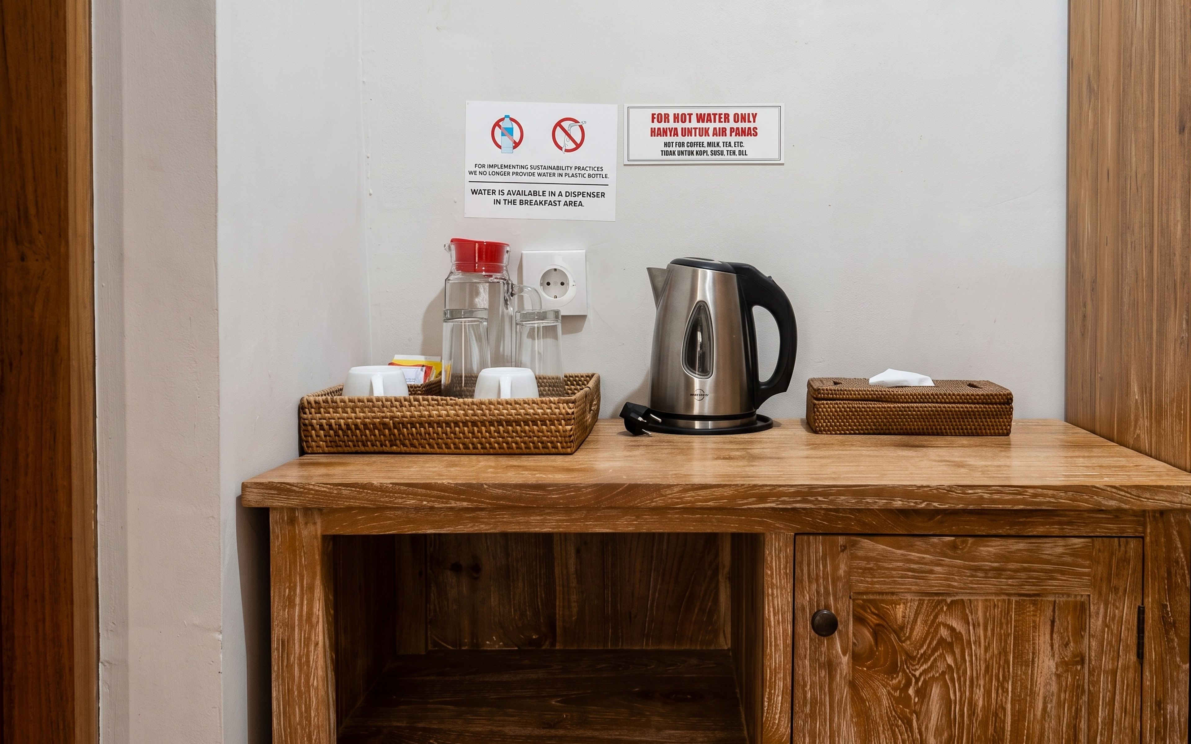 Un comedor con cafetera, hervidor y dispensador de agua sobre una mesa de madera.