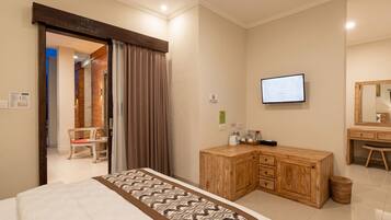 Quarto de hotel com uma cama, escrivaninha de madeira, televisão e espelho.