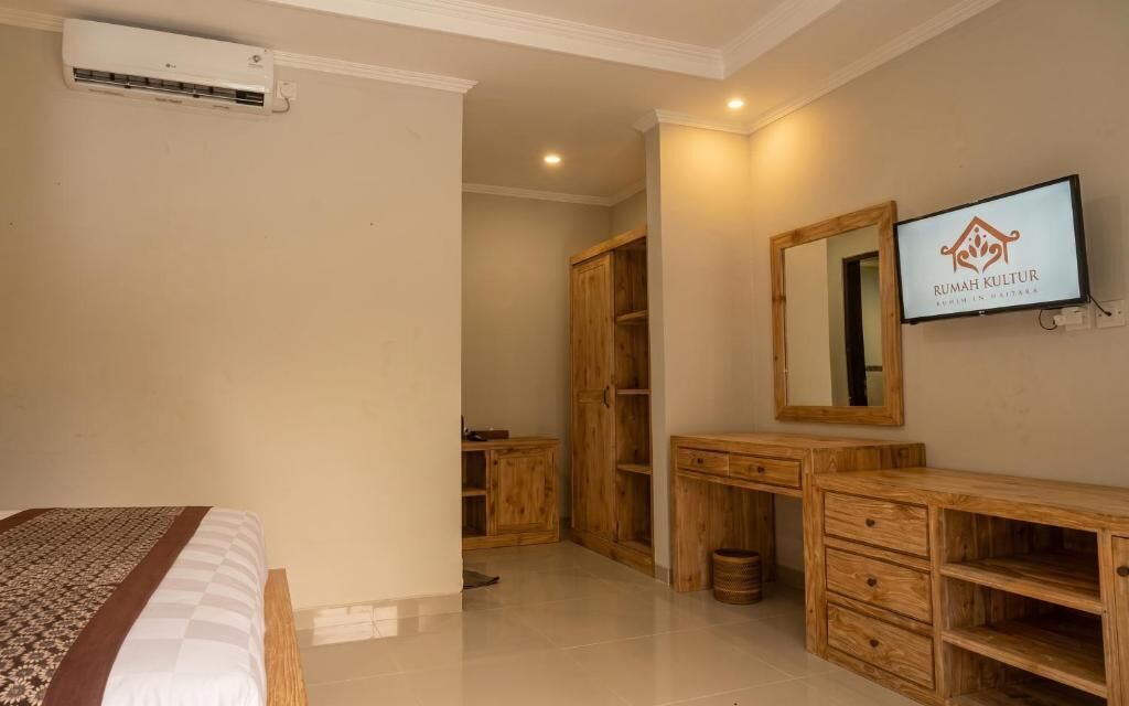 Un dormitorio con cama, armario de madera, televisor y espejo.