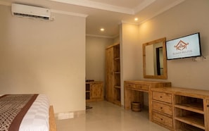 A bedroom with a bed, wooden wardrobe, a TV, and a mirror. - Rumah Kultur (Ubud)