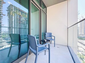 A balcony with two chairs and a small table, large windows with a view of a cityscape and construction. - Modern 1BR Retreat in Parkside Views | Dubai Hills (Dubai)