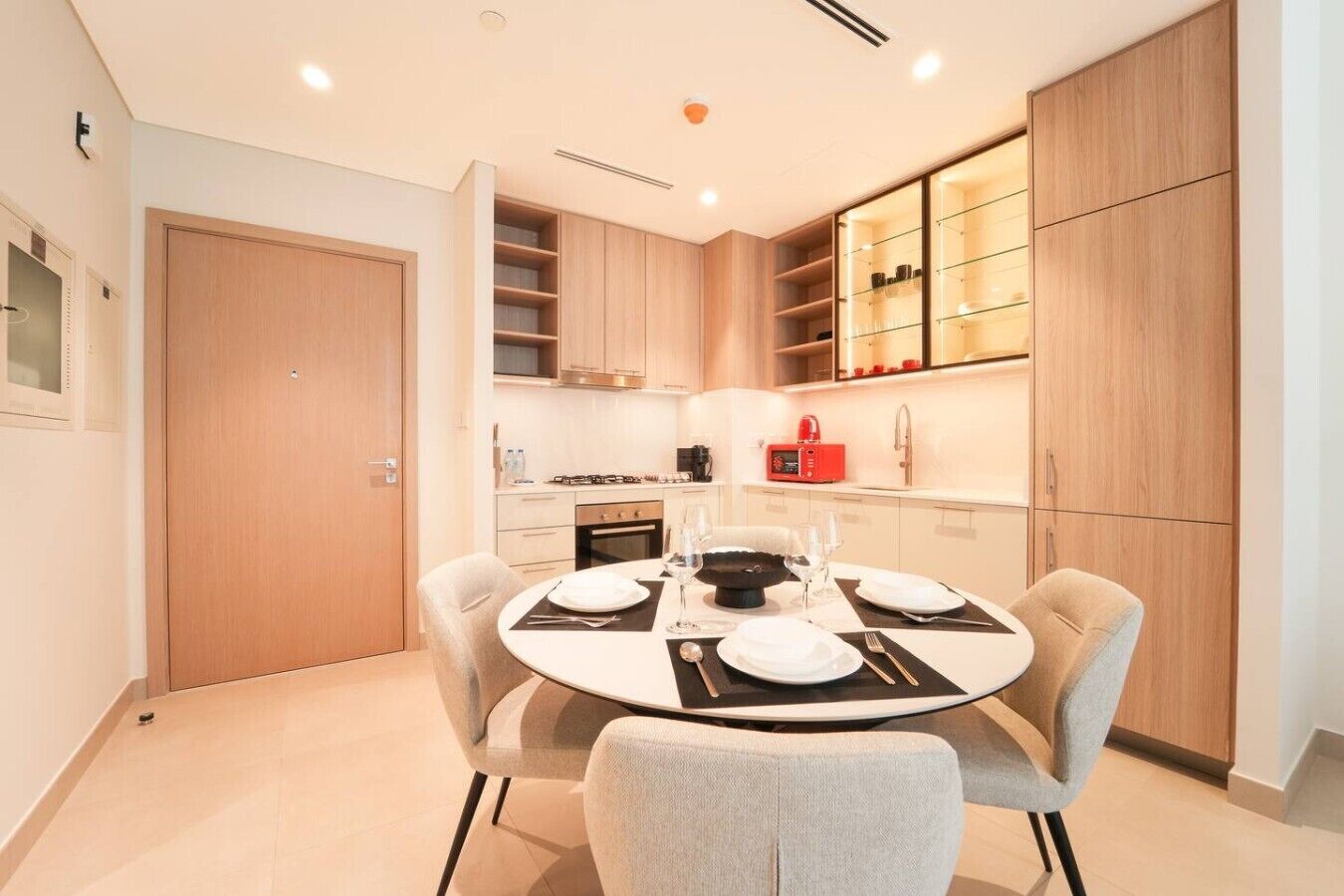 A modern kitchen with a dining area, featuring a round table, chairs, and a built-in oven.