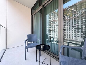 Un balcon avec deux fauteuils en osier et une petite table, donnant sur un chantier de construction.