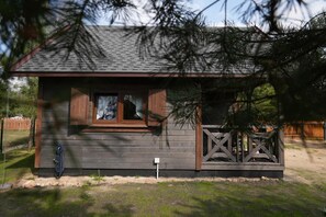 A small wooden cabin with a window, a door, and a fenced porch.