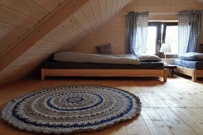 A loft bedroom with a sloped ceiling, a bed, a bedside table, a lamp, and a patterned rug.