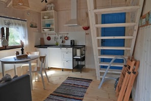A compact kitchen with white cabinets, a dining table with chairs, a colorful rug, and a blue door. - Nasze Podlasie - Cottage in Dubicze Cerkiewne (Dubicze Cerkiewne)