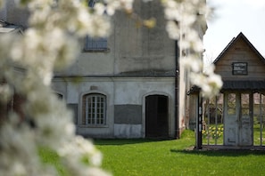 A building with a large arched window, a smaller arched doorway, and a sign indicating a workshop or factory.