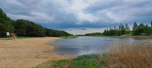 A riverbank with a sandy area, a metal structure, and dense trees in the background. - Nasze Podlasie - Cottage in Dubicze Cerkiewne (Dubicze Cerkiewne)