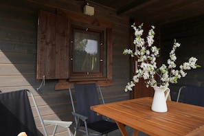 A wooden table with a white vase containing white flowers, a window with wooden shutters, and a chair. - Nasze Podlasie - Cottage in Dubicze Cerkiewne (Dubicze Cerkiewne)