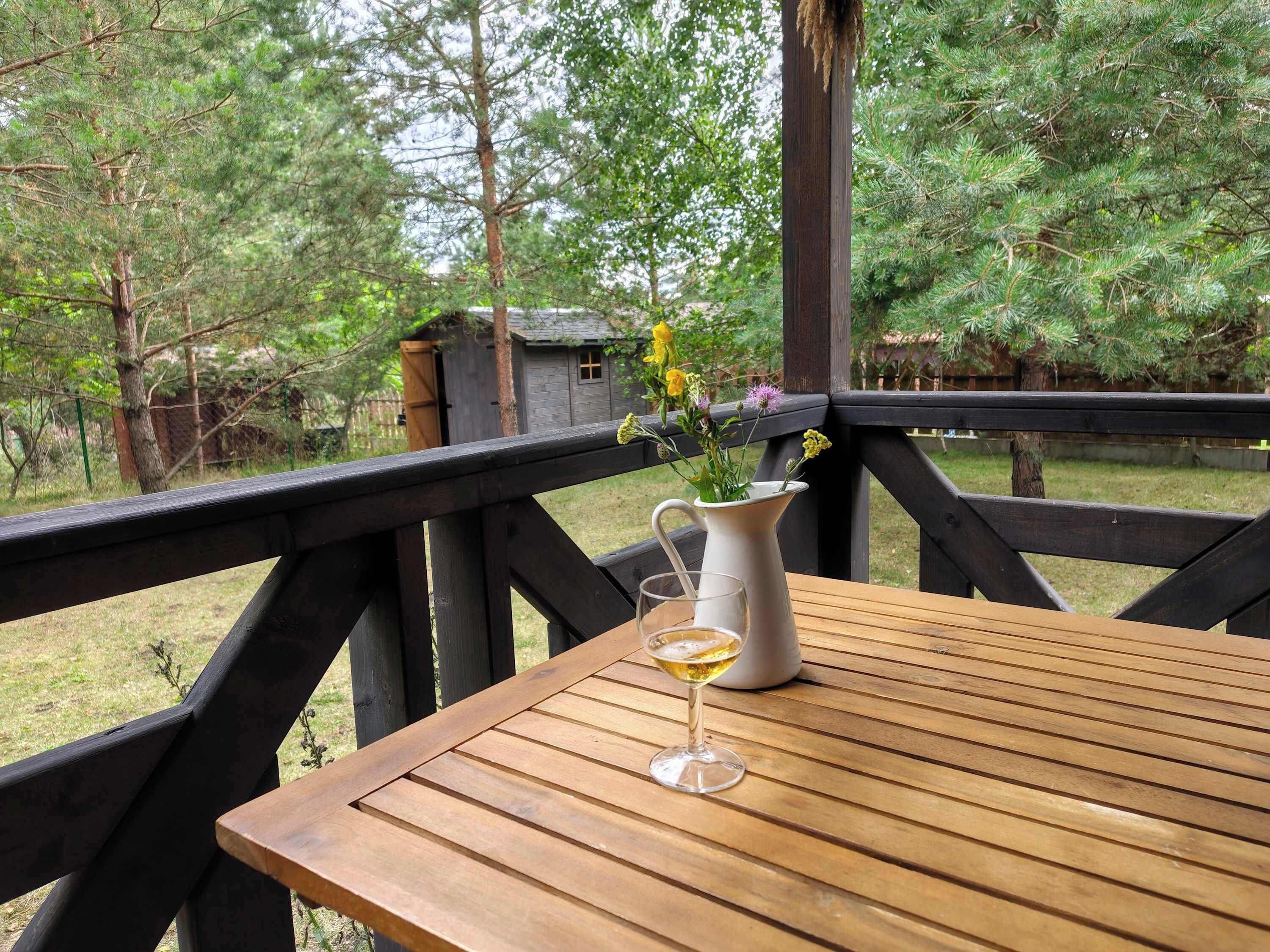 Eine Holzterrasse mit Tisch und einem Blumenkrug.