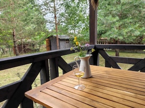A wooden deck with a table and a pitcher of flowers.