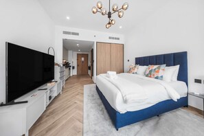 Une chambre d’hôtel moderne équipée d’un grand lit, d’une télévision, d’une armoire et d’une kitchenette.