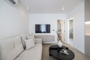 A modern living room with a sofa, a coffee table, and a flat-screen TV mounted on the wall. - Apex Refined Apartment Antun Zadar (Zadar)