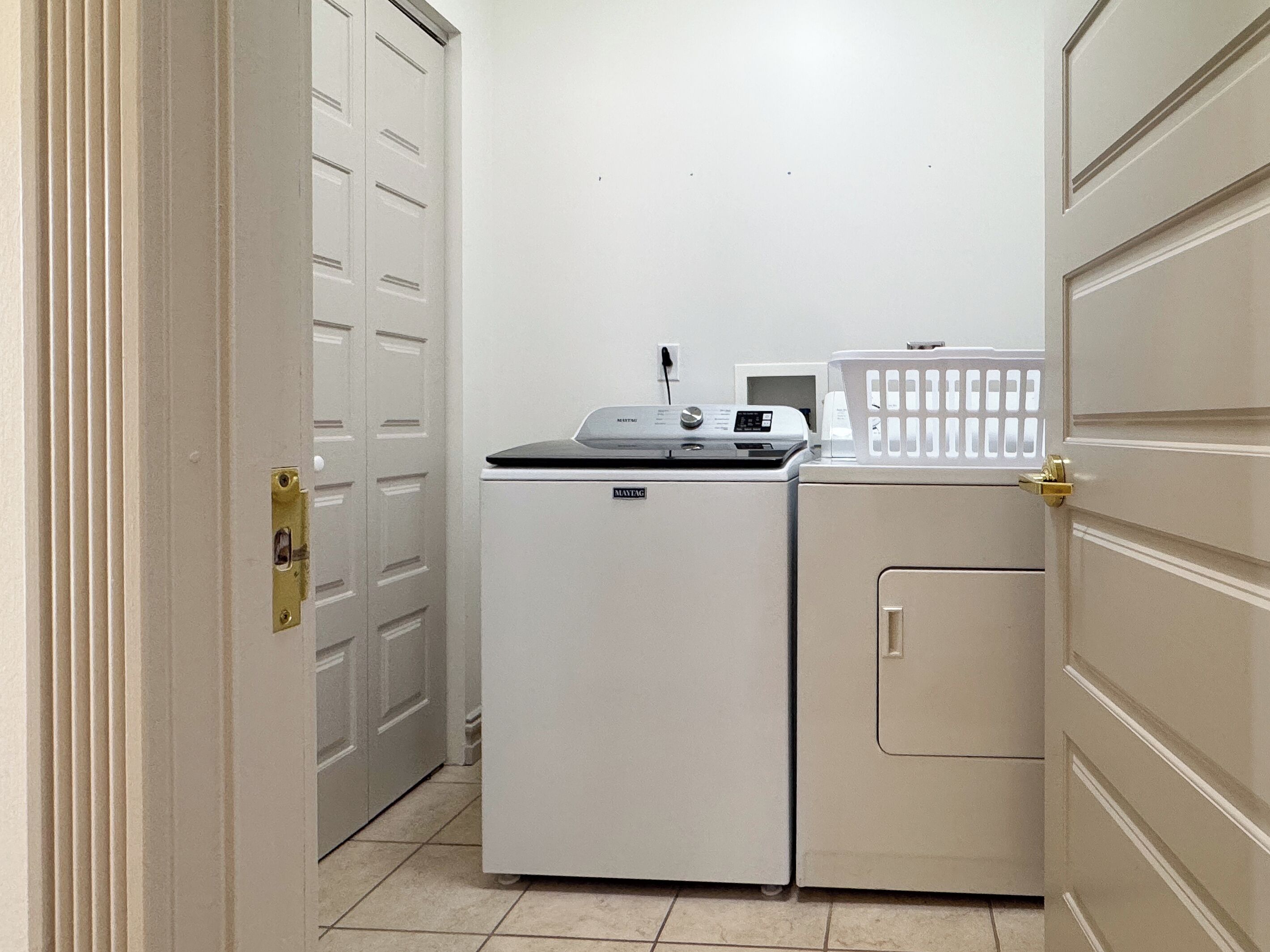 A laundry room with a washing machine, dryer, and a basket.