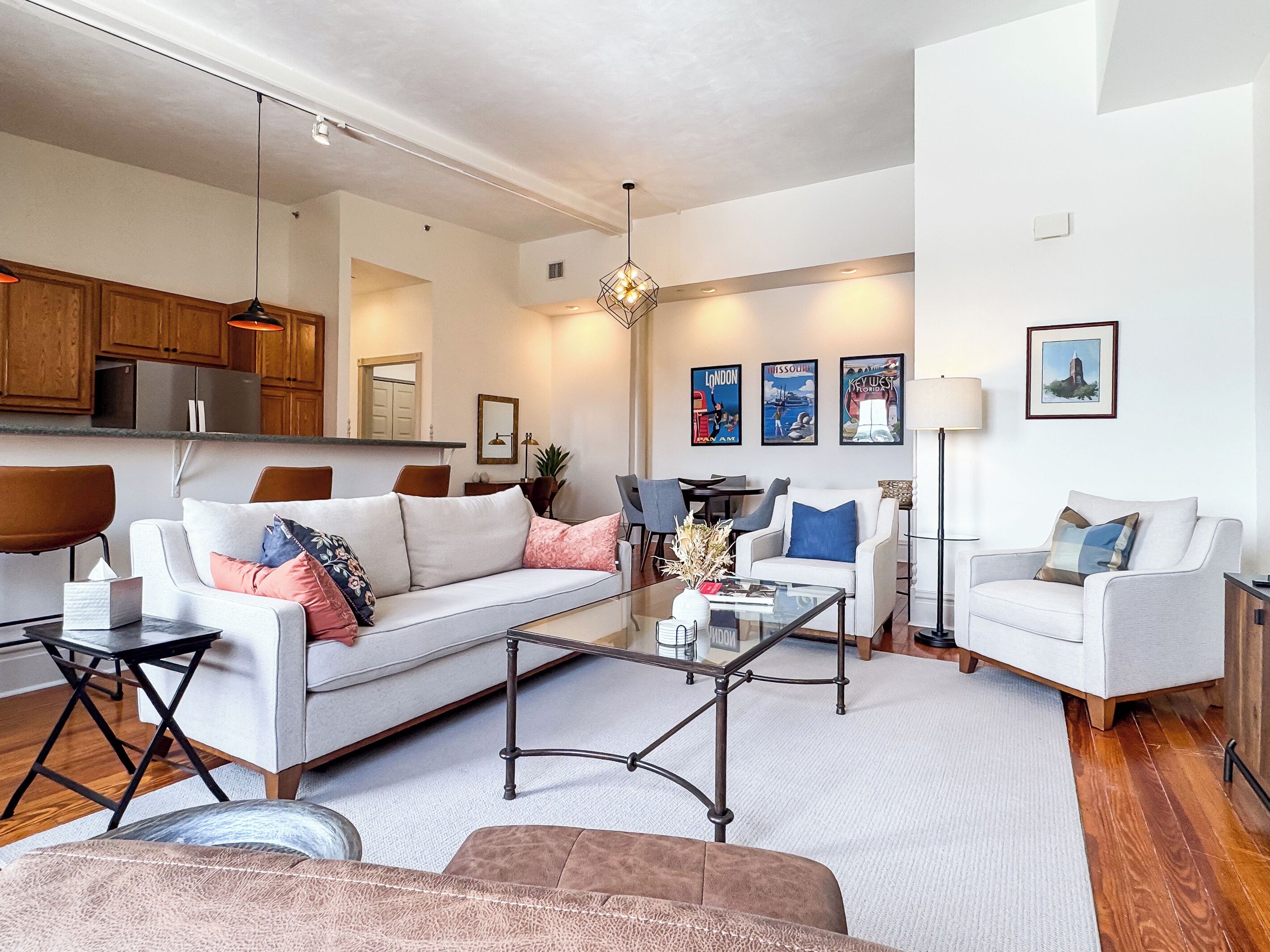 A modern living room with a sofa, armchairs, a coffee table, and a dining area with chairs and a table.