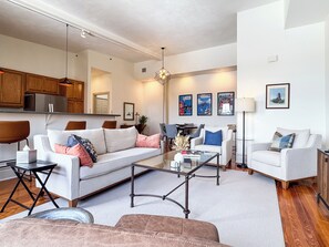A modern living room with a sofa, armchairs, a coffee table, and a dining area with chairs and a table.