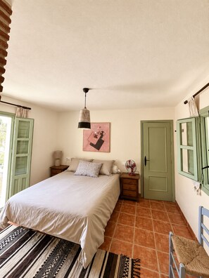 A bedroom with a bed, bedside tables, a hanging lamp, a door, and a window with curtains. - Welcome to Casa Berberi (Montejaque)