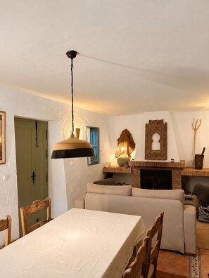 Ein Essbereich mit Tisch und Stühlen, einer Couch, einem Kamin und einer Hängeleuchte.