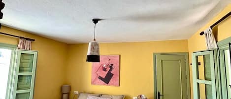 A bedroom with a bed, a nightstand, a lamp, a door, and a window.
