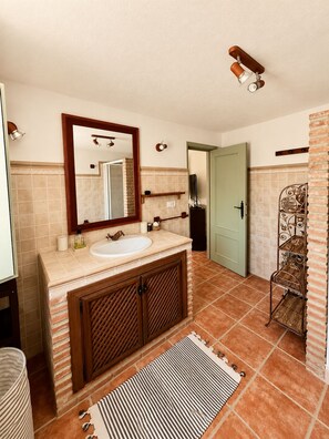 A bathroom with a sink, mirror, and a shower area. - Welcome to Casa Berberi (Montejaque)