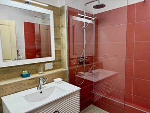 Un bagno moderno con doccia vetrata, lavandino bianco e specchio sopra.