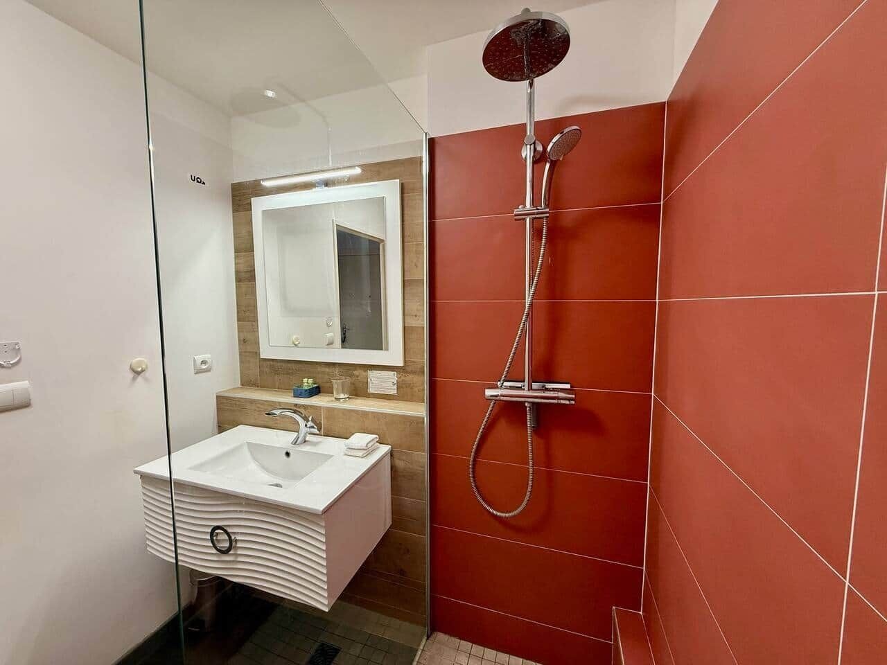 A modern bathroom with a glass-enclosed shower, a white sink, and a wooden vanity.