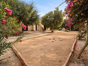 A courtyard with a croquet lawn, surrounding trees, and a stone building. - Palais Amani (Aït Chouer)