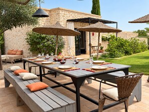 An outdoor dining area with a stone wall backdrop, a table set for four, and a bench seating arrangement. - Palais Amani (Aït Chouer)