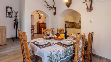 A dining area with a table set for four, surrounded by wooden chairs with carved details.