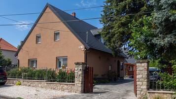 Una casa de dos pisos con techo inclinado, un portón de piedra y un camino de entrada pavimentado.