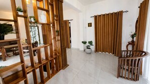 A modern interior with a wooden partition, a dining area with a bench, a potted plant, and a curtain.
