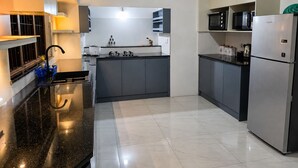 A modern kitchen with a black countertop, stainless steel appliances, and grey cabinetry.