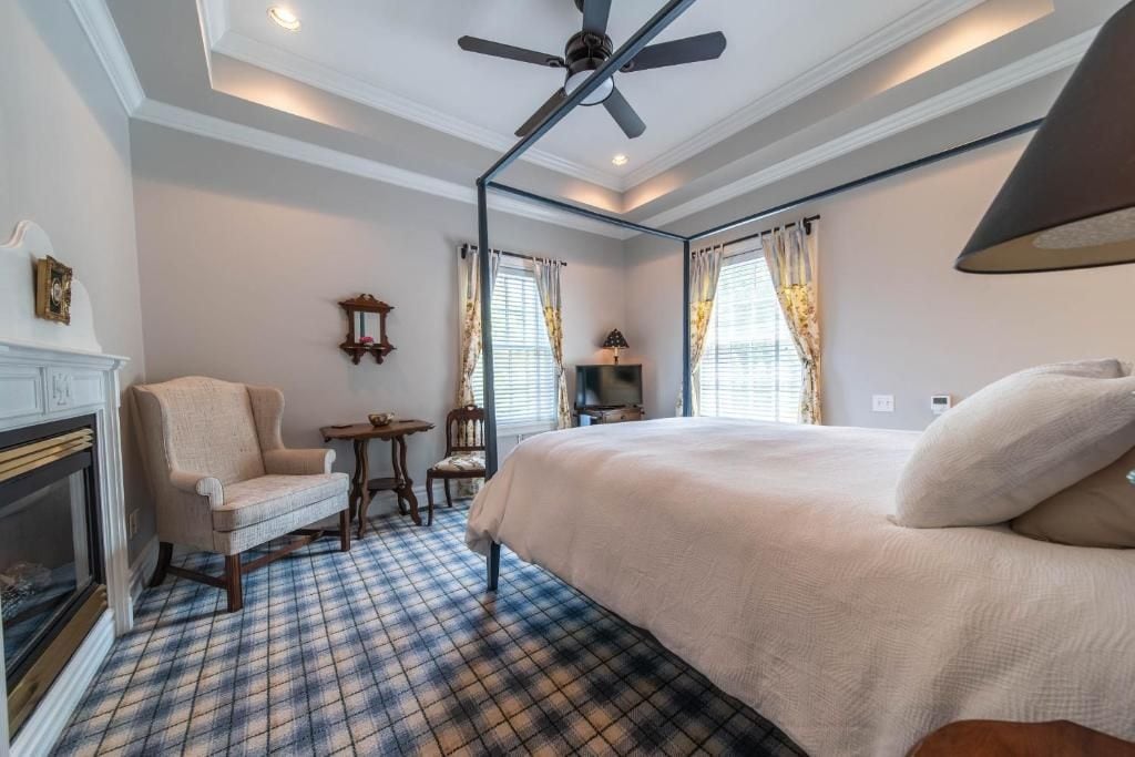 Une chambre à coucher comprenant un lit, une chaise, une petite table, une cheminée et un ventilateur de plafond.