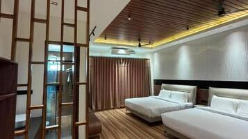 A hotel room with a wooden floor, two beds, a wardrobe, and a sliding door.