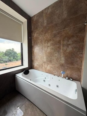 Une salle de bain moderne avec une grande baignoire, une fenêtre et une vue sur l’extérieur.