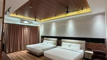 Habitación de hotel moderna con techo inclinado, dos camas, zona de estar y un ventanal grande.