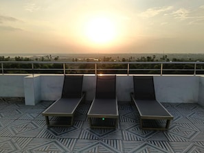 Une terrasse sur le toit avec trois chaises longues et un sol à motifs.