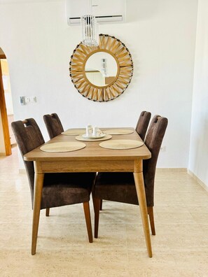 Ein Essbereich mit einem Holztisch, sechs Stühlen und einem dekorativen Spiegel an der Wand.