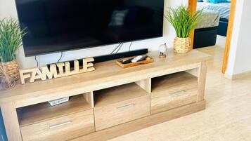 En moderne stue med et fladskærms-tv på et træ-tv-bord med teksten 'FAMILIE'.