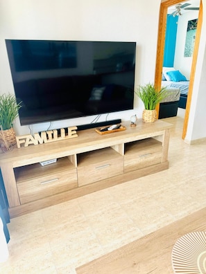 Una sala de estar moderna con un televisor de pantalla plana sobre un mueble de madera con la etiqueta 'FAMILY'.