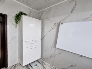 Un baño con un mueble blanco, paredes de mármol y una pizarra.