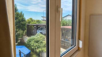 Ein Fenster mit Blick auf einen Garten, einen Zaun und ein Auto.