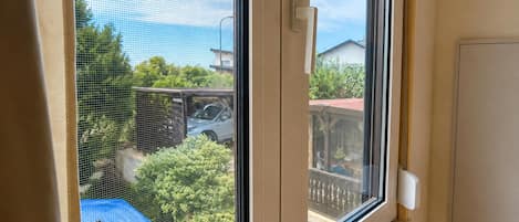 A window with a view of a backyard, a fence, and a car.