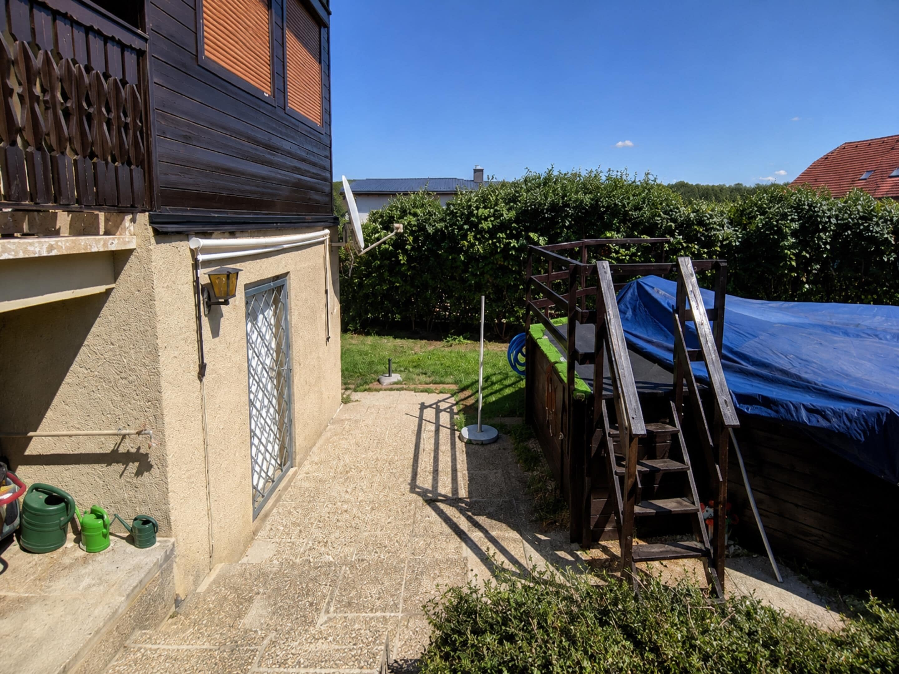Ein Wohnhaus mit befestigter Auffahrt, einer Holzterrasse und einem überdachten Außenbereich.